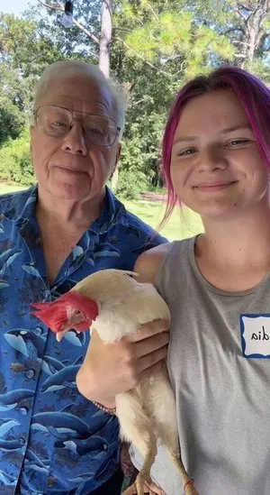 Claudia holding a chicken beside Bob Bailey